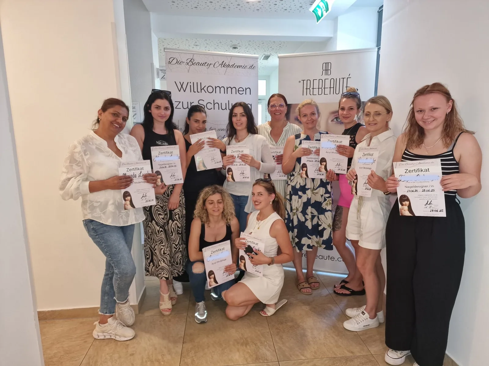 Teilnehmerinnen der Nageldesign-Ausbildung halten am letzten Kurstag ihre Zertifikate in die Kamera